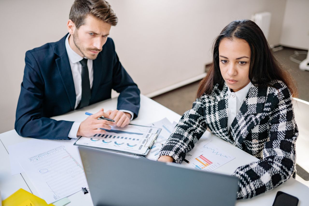 Two colleagues reviewing automation dashboards on laptops